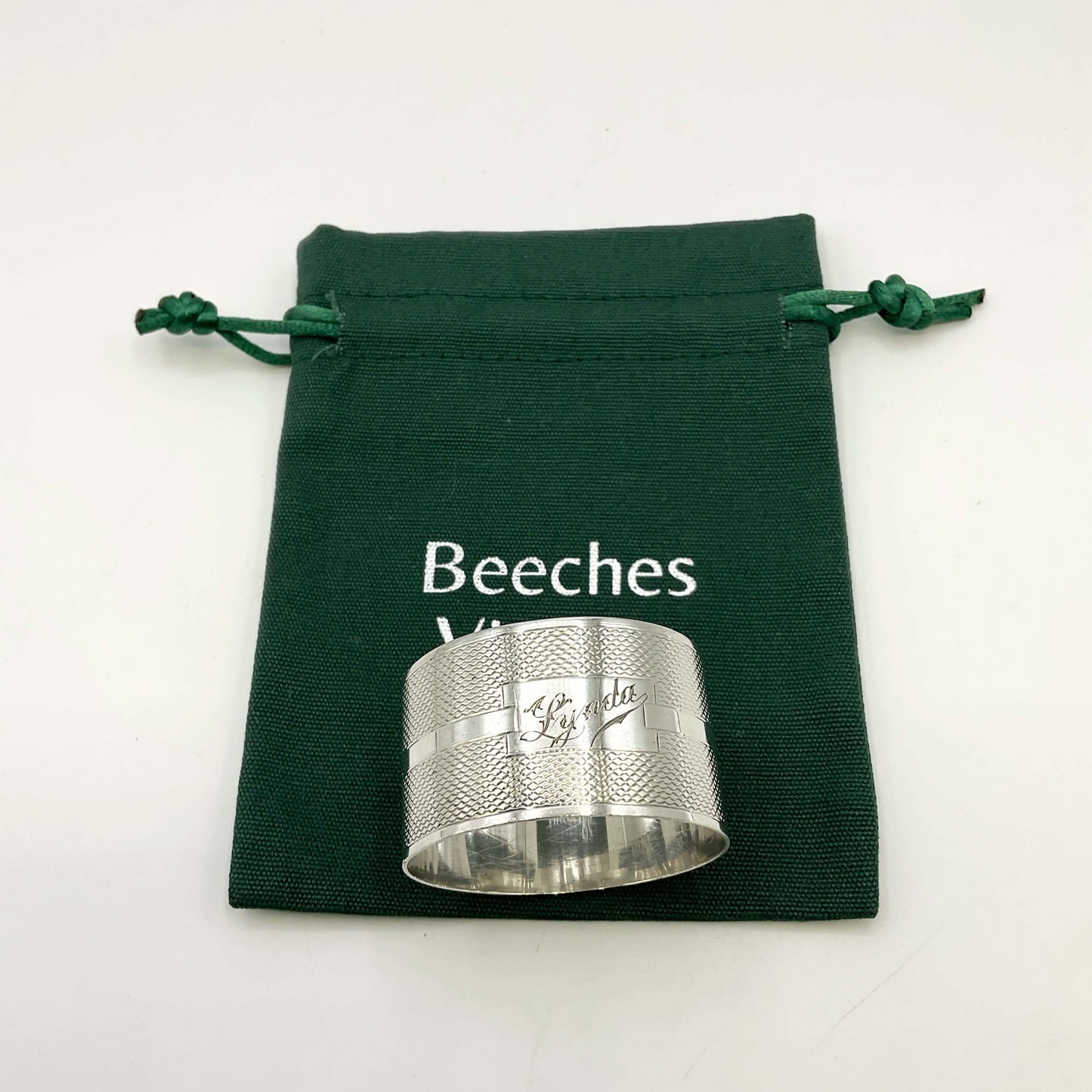 Silver napkin ring with Lynda on on the front on a gift bag on a white background 