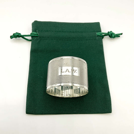 Silver napkin ring with LAW engraved on the front on a green gift bag and white background 