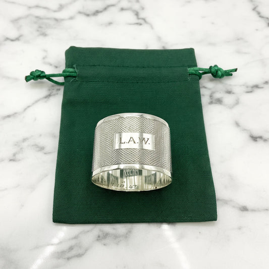 Silver napkin ring with LAW engraved on the front on a green gift bag and white background 