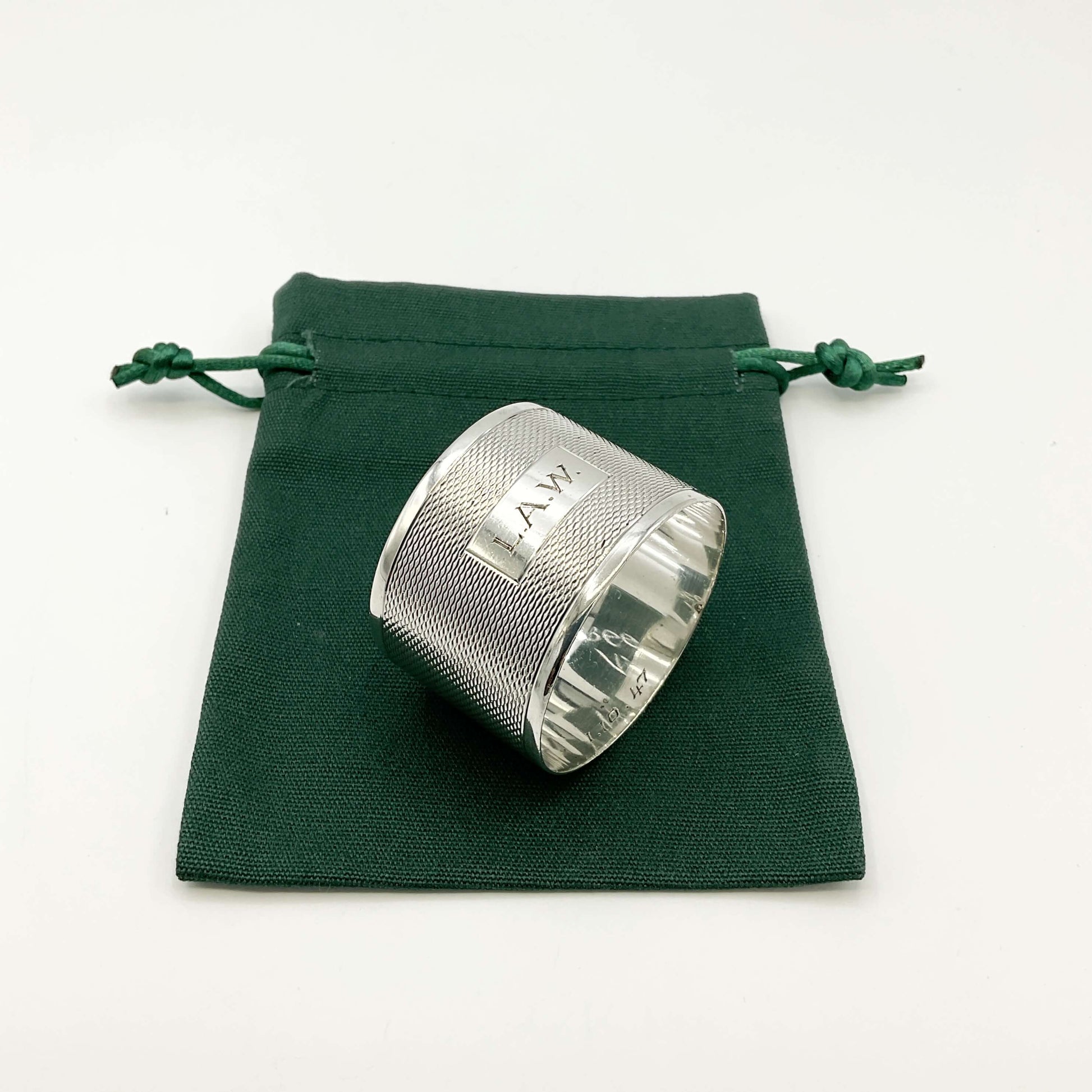 Silver napkin ring with LAW engraved on the front on a green gift bag and white background 