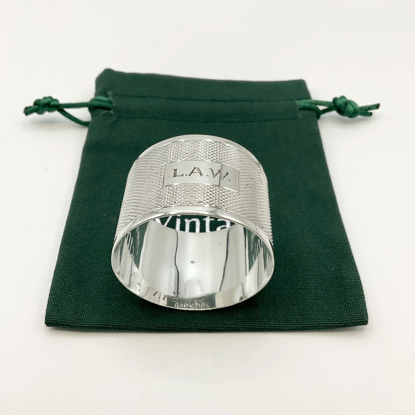 Silver napkin ring with LAW ngraved on the front on a green gift bag and white background 