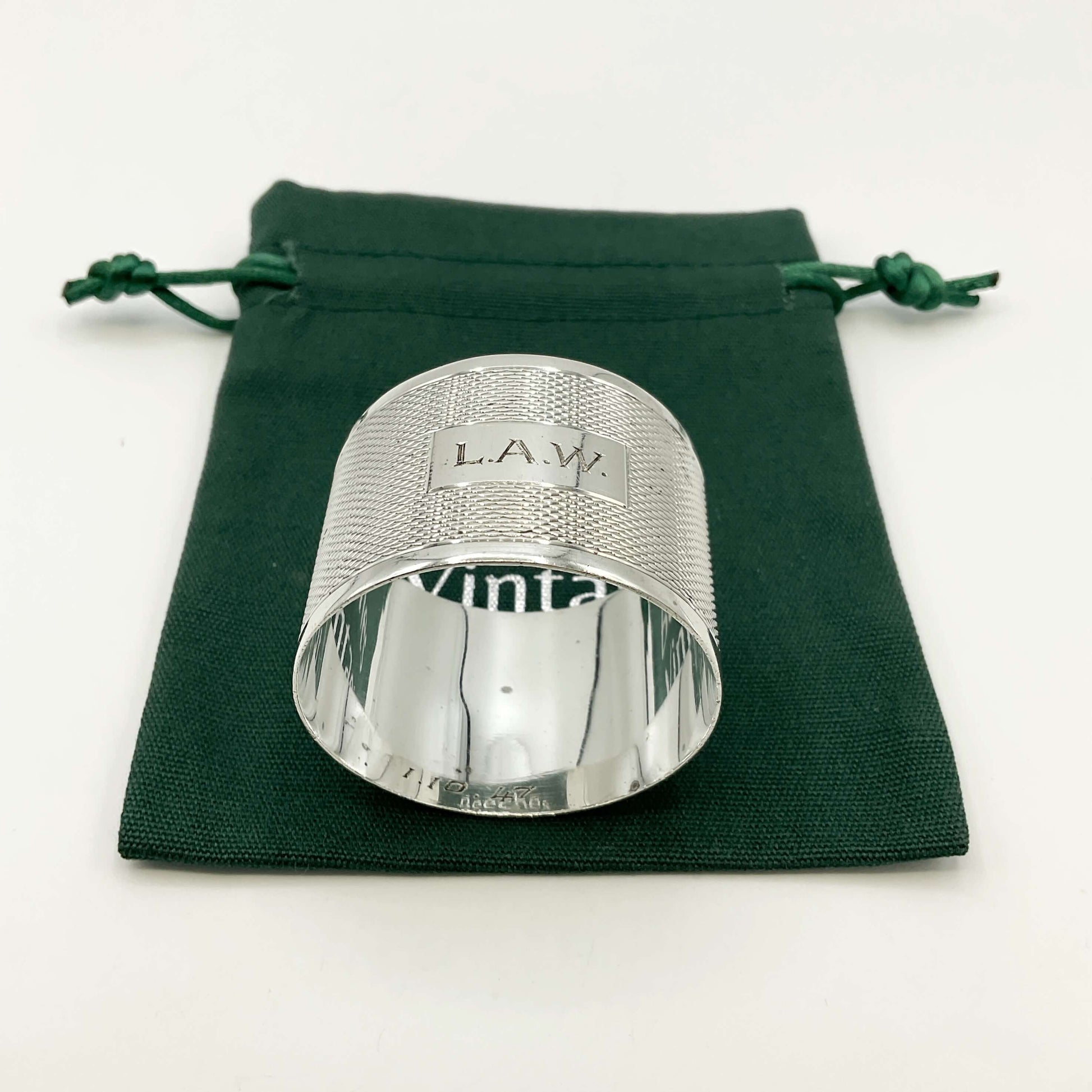 Silver napkin ring with LAW ngraved on the front on a green gift bag and white background 
