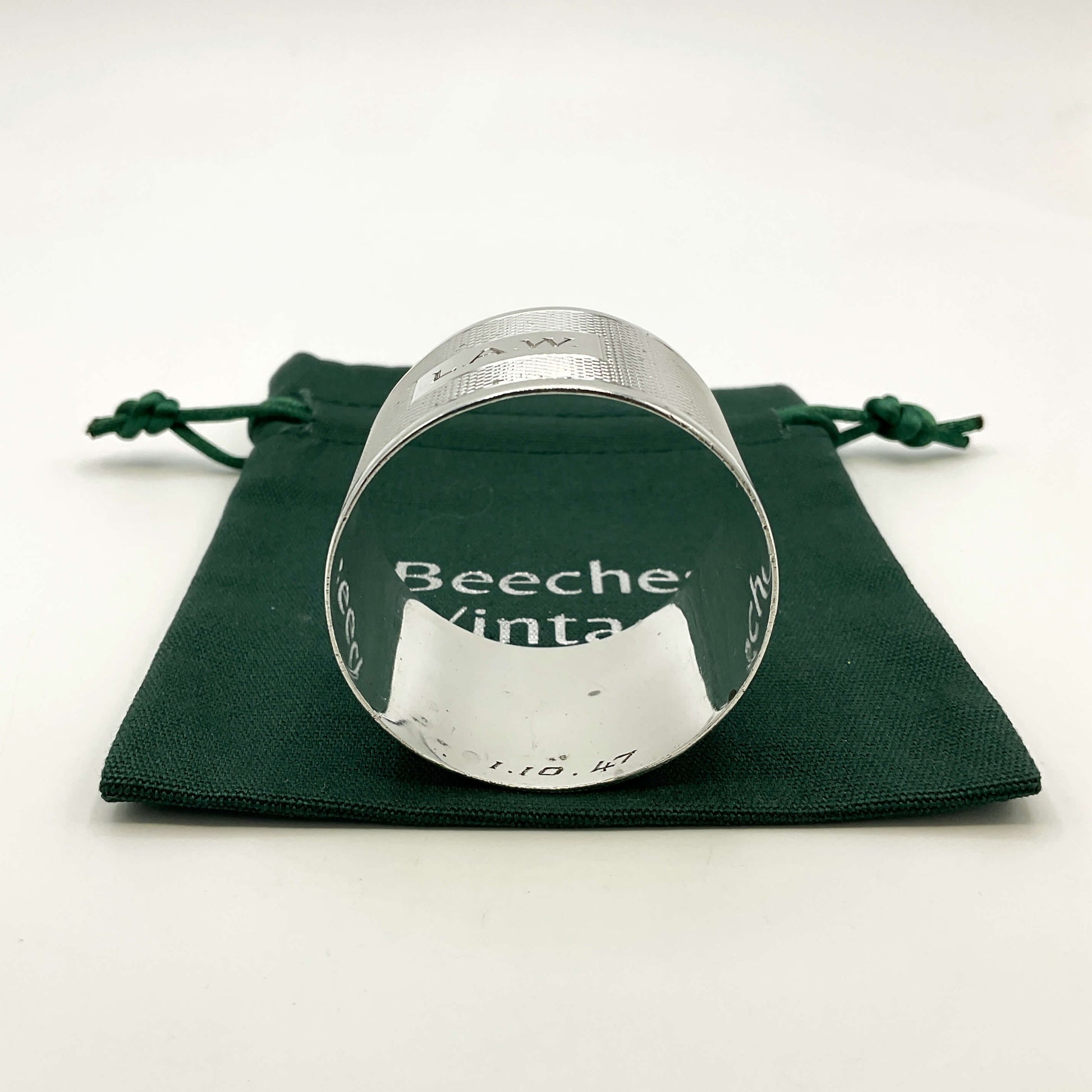 Inside of Silver napkin ring with LAW engraved on the front on a green gift bag and white background 