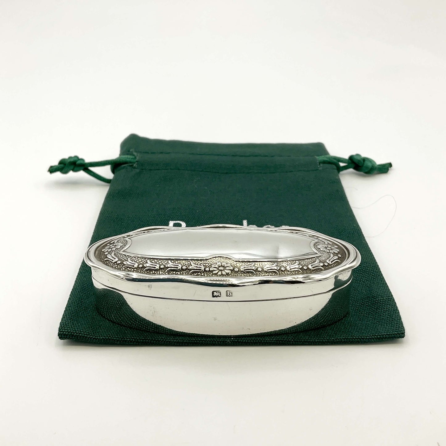 Small Antique silver jewellery box on a green gift bag and a white background 