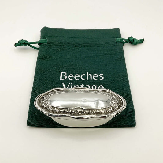 Small Antique silver jewellery box on a green gift bag and a white background 