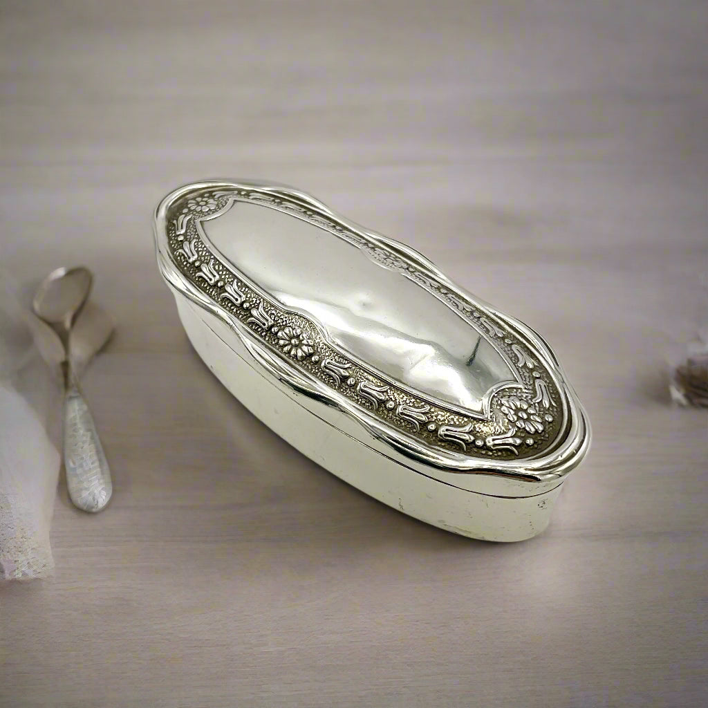 Silver jewellery box on a wood table with dressing table items around it