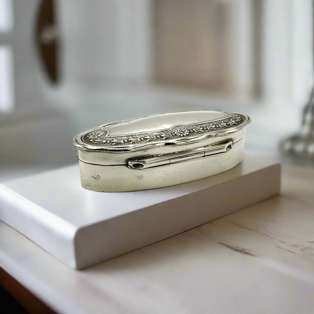 Back of Small Antique silver jewellery box on a light wood dressing table 