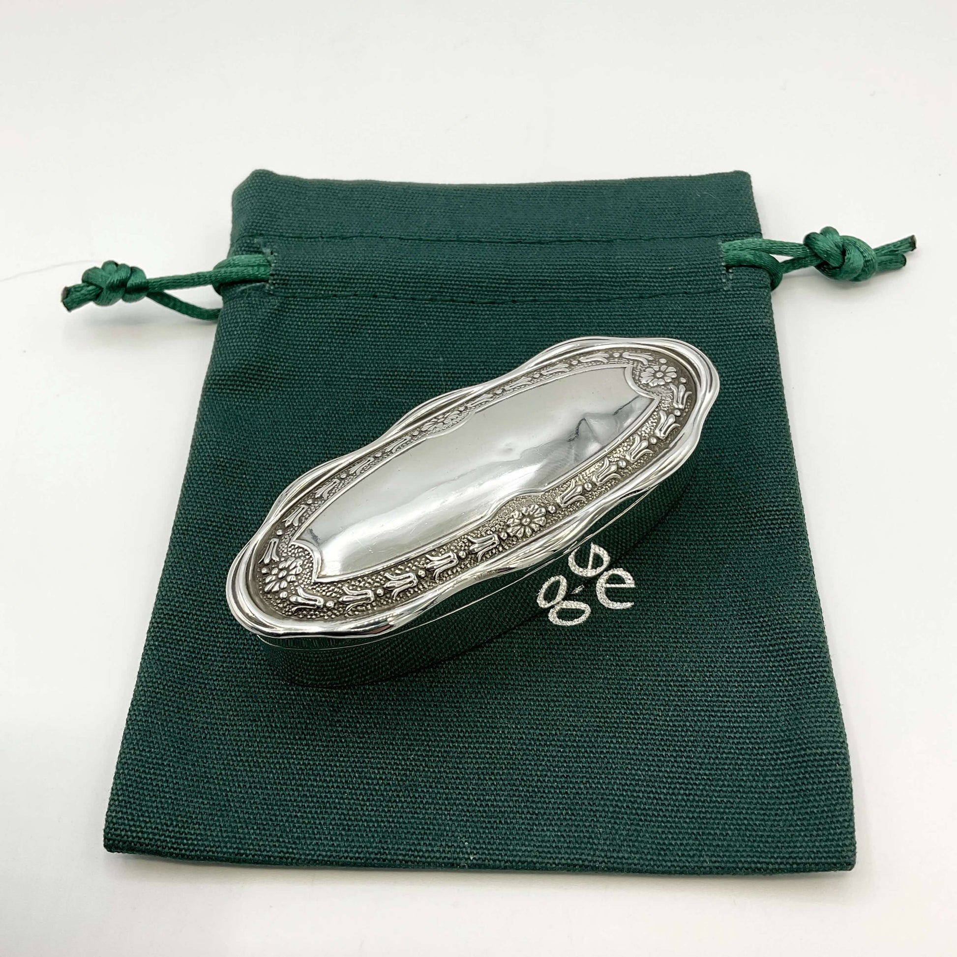 Small Antique silver jewellery box on a green gift bag and a white background 