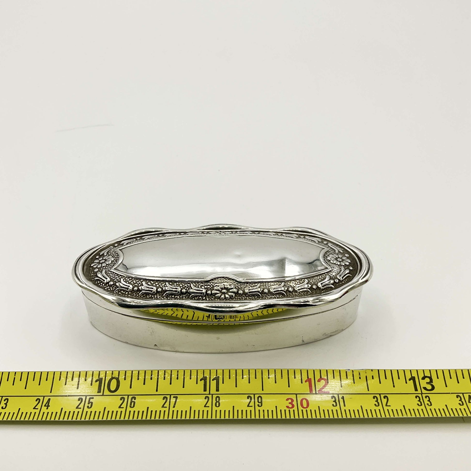 Small Antique silver jewellery box next to a tape measure on a white background showing the width as 3 inches