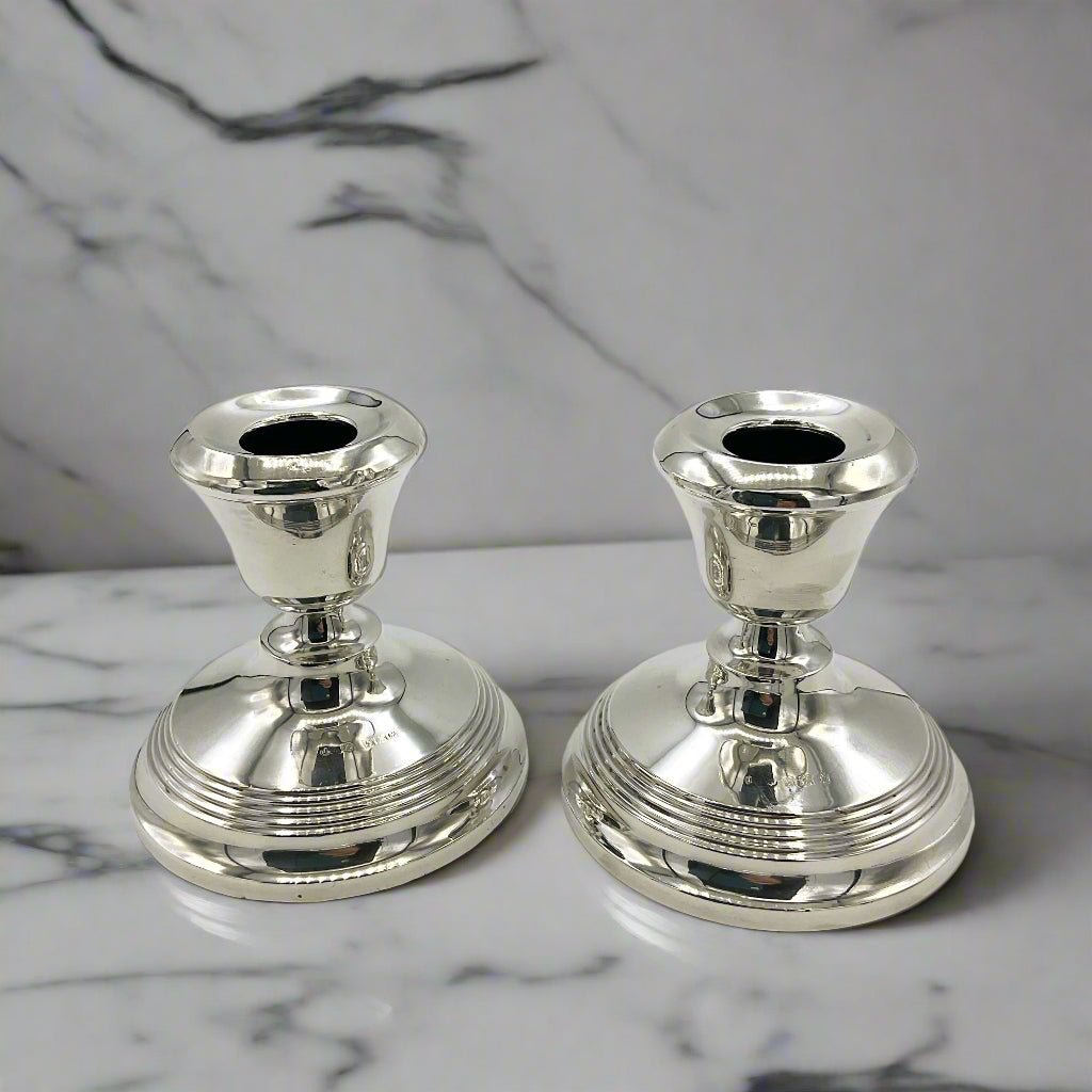 two silver candle holders on a marble worktop