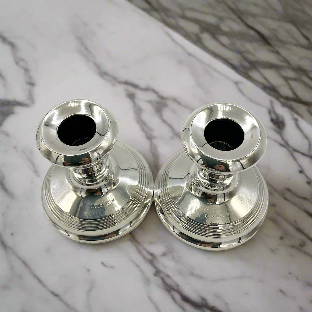 Two silver candle holders next to each other on a marble worktop