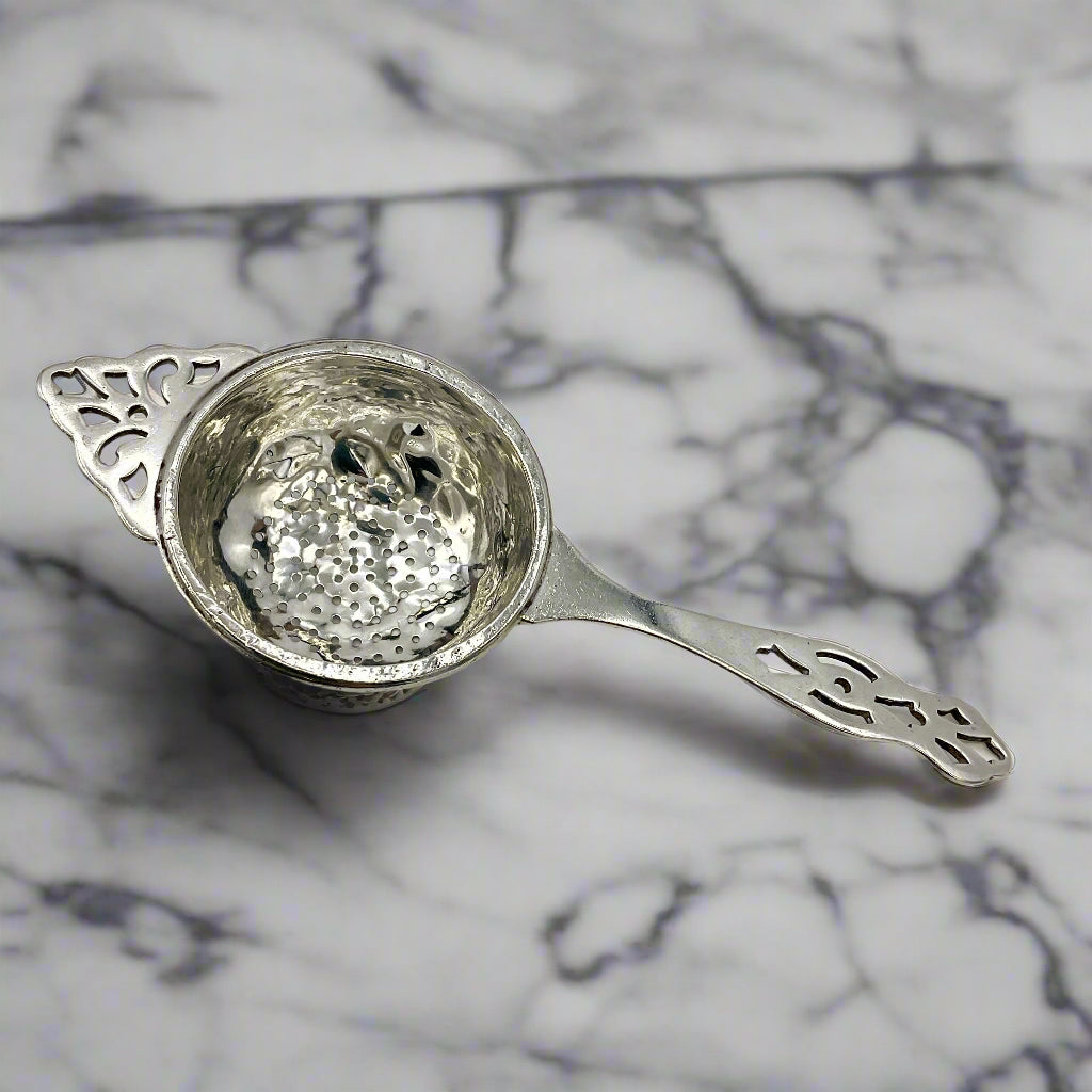 Silver tea strainer on a marble worktop