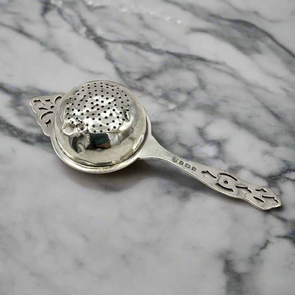 Silver tea strainer upside down on a marble worktop