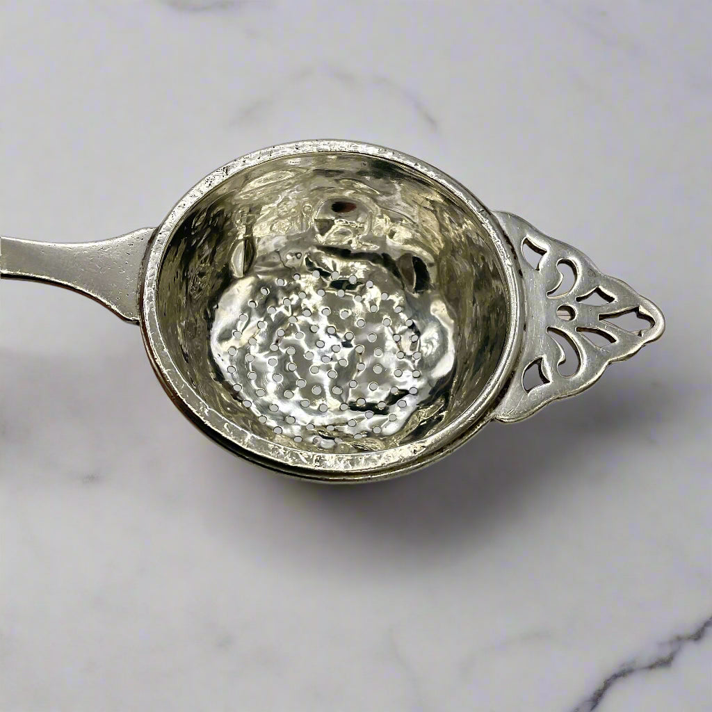 Silver tea strainer bowl with a marble worktop background 