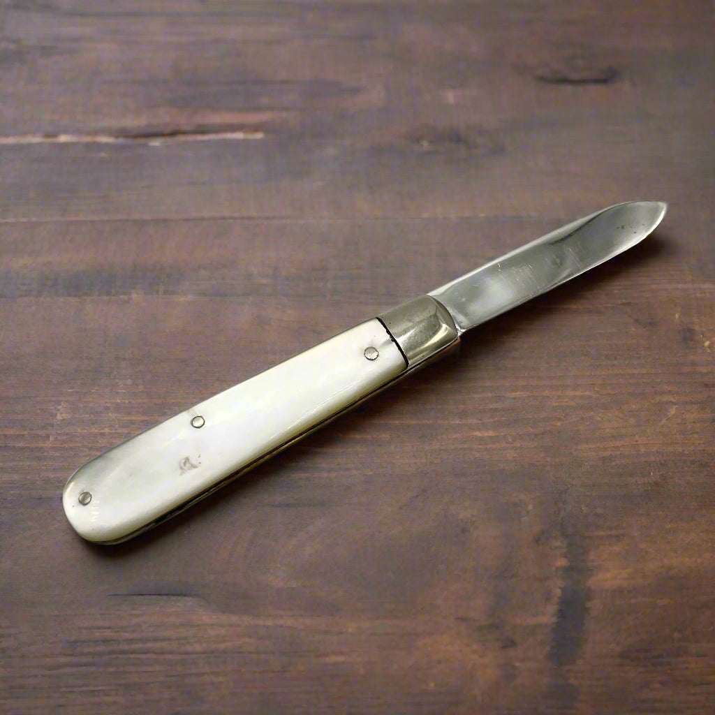 Back of a silver fruit knife on a dark wood table