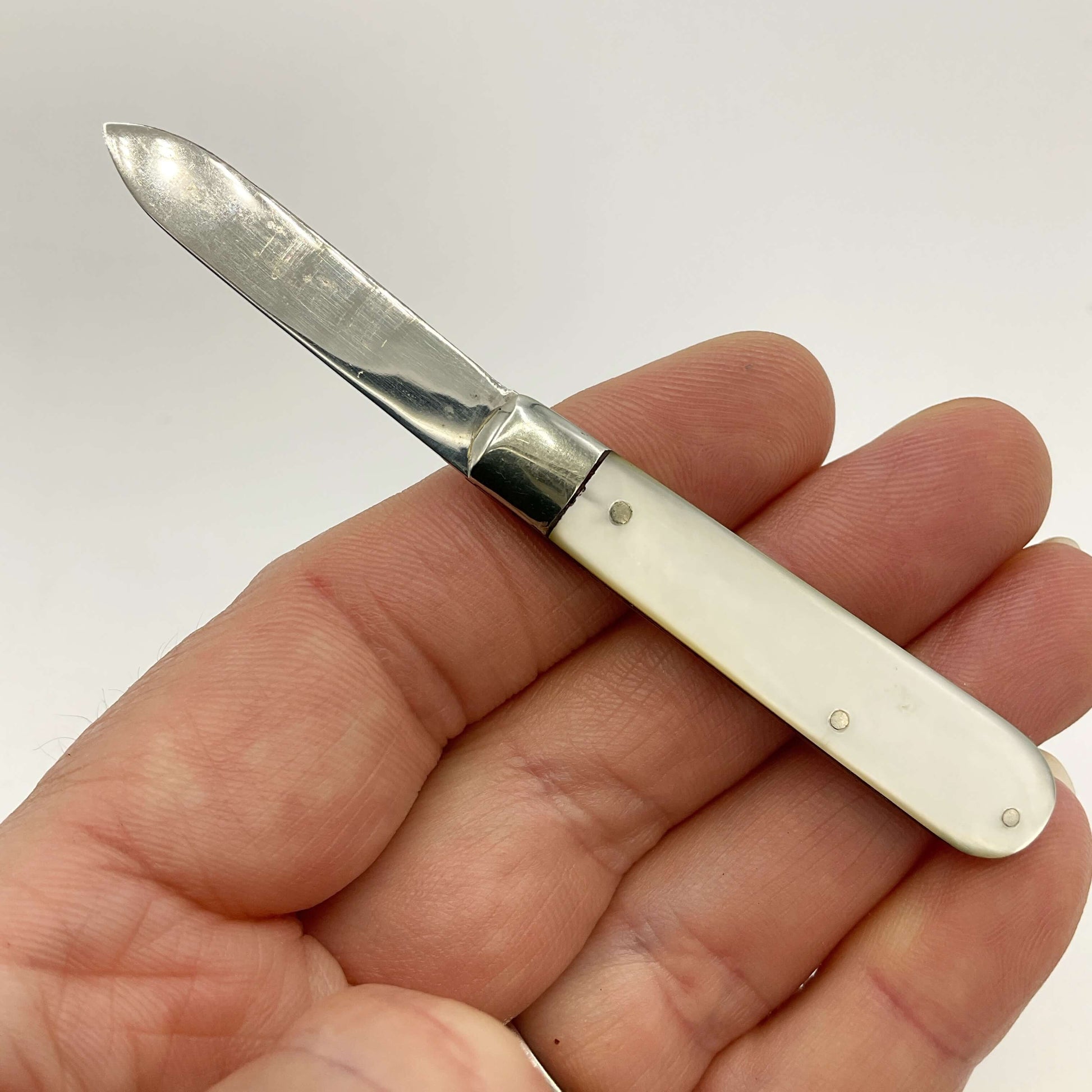 Silver fruit knife held I a hand with a white background 