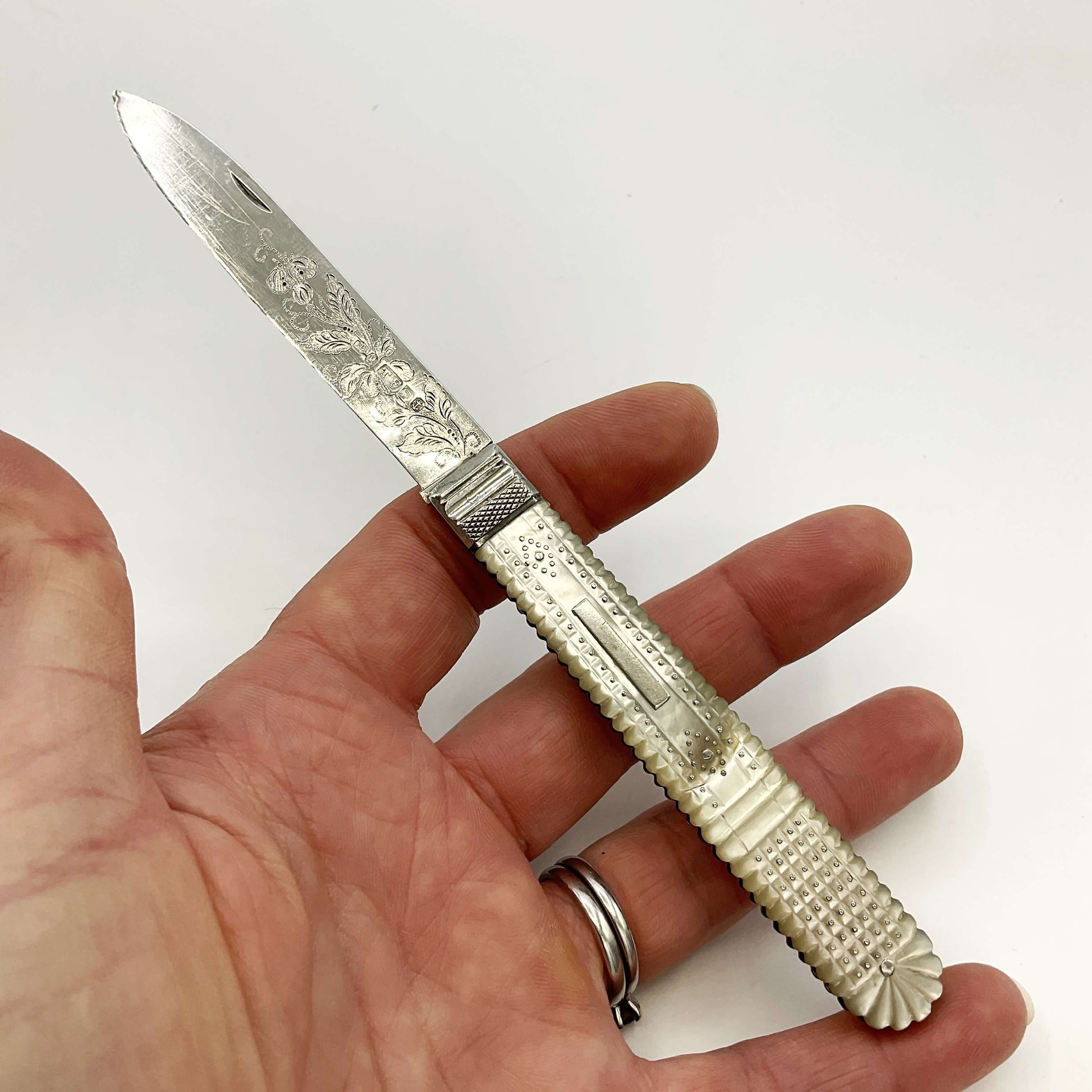 Antique silver fruit knife Held in a hand with a white background 
