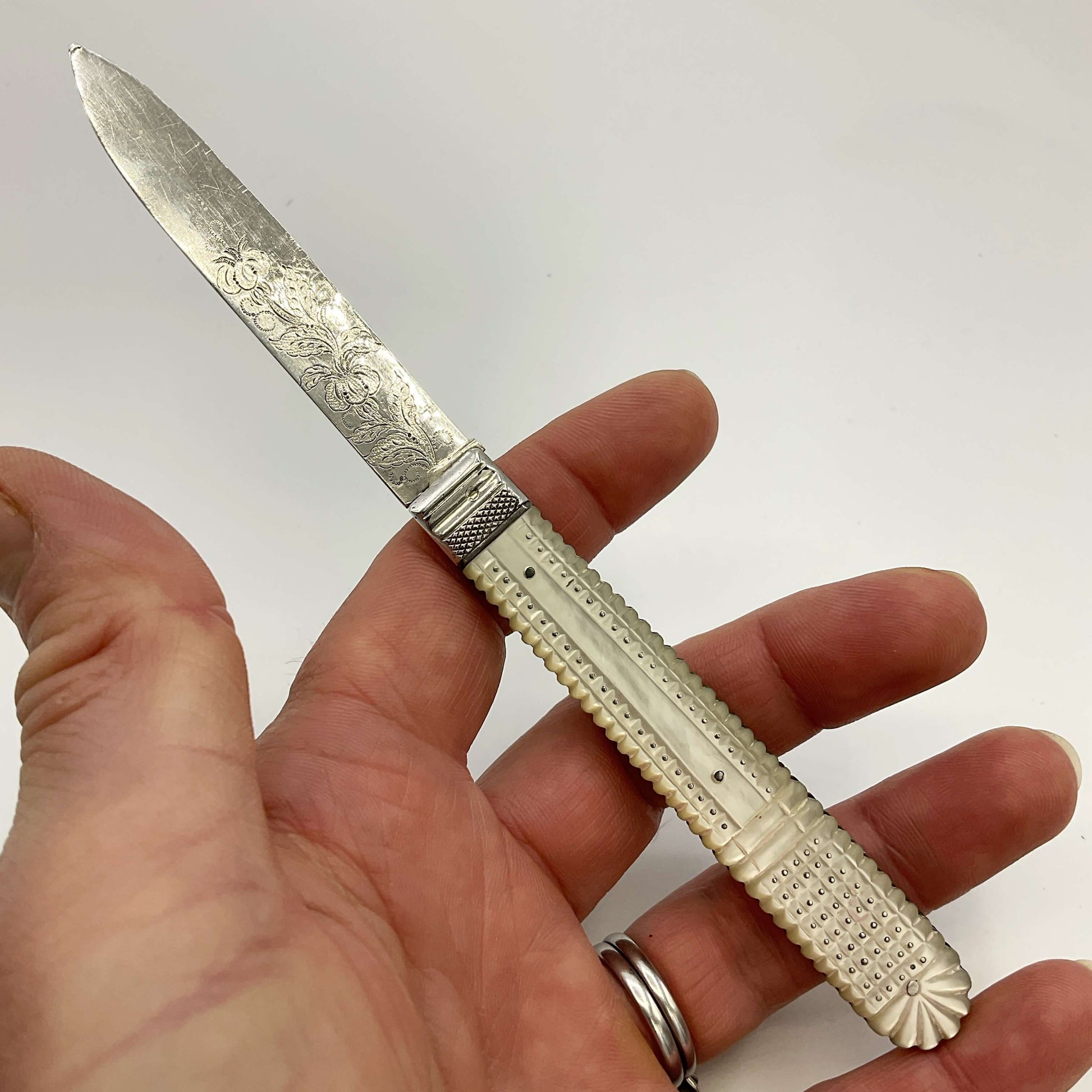 Back of a Antique silver fruit knife held in a handle with a white background 
