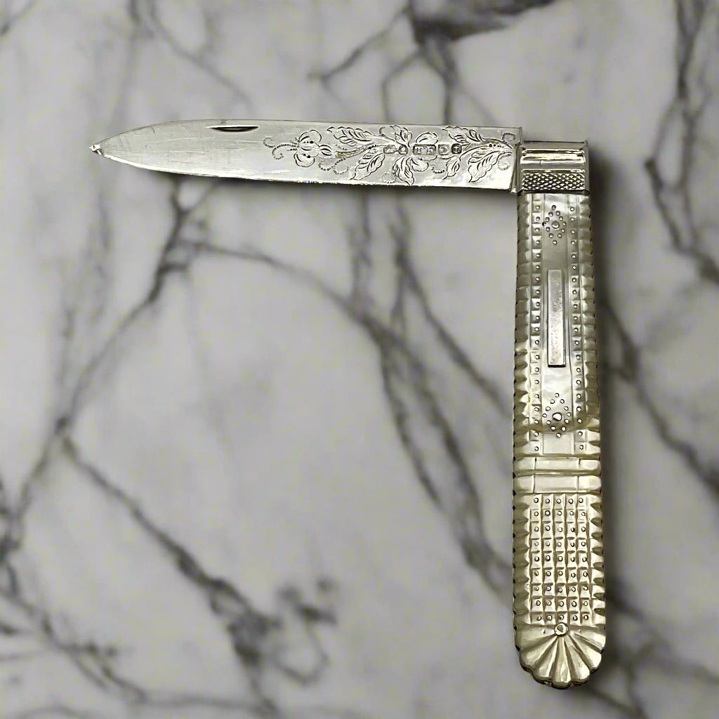 Antique silver fruit knife Half folded on a marble worktop