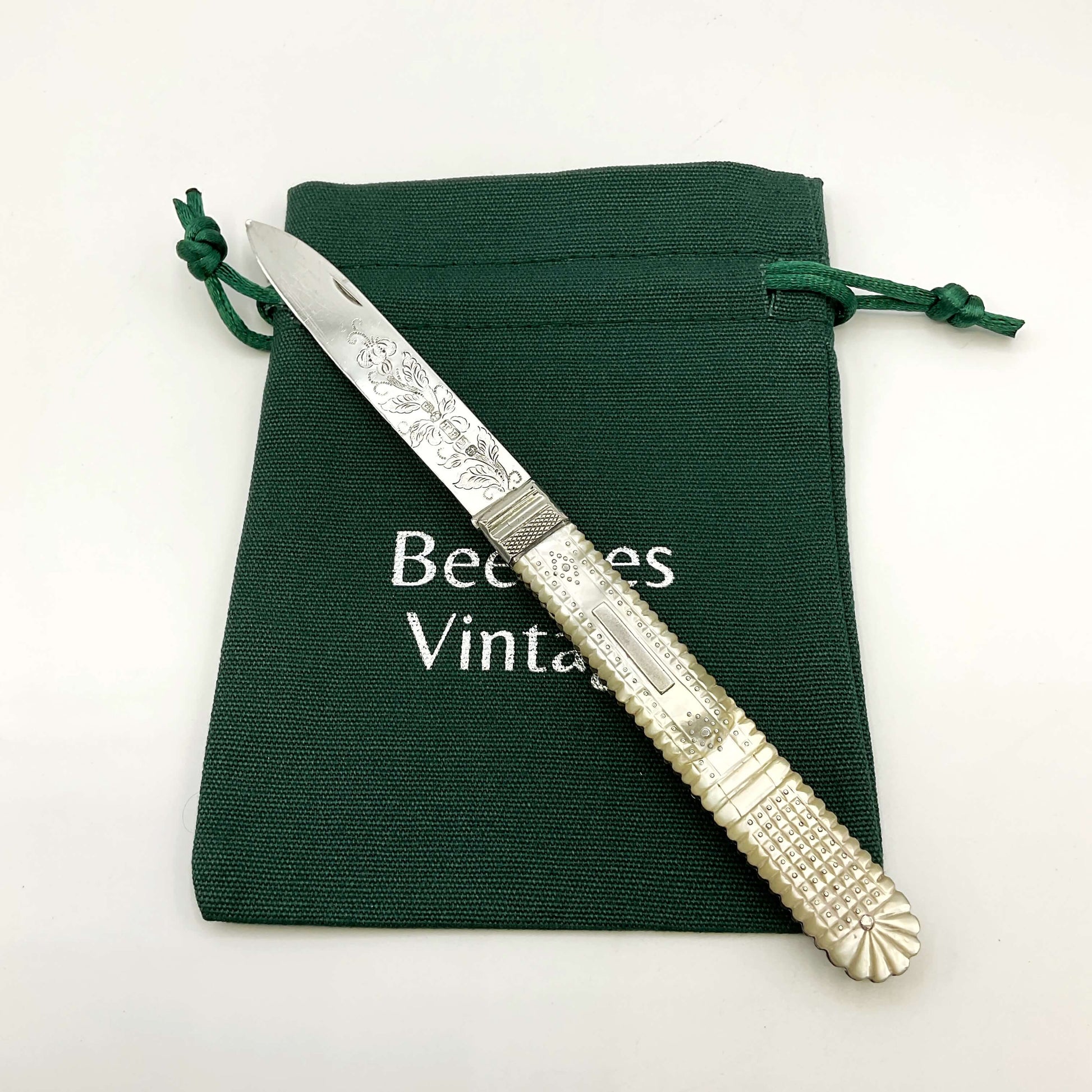 Antique silver fruit knife on a green gift bag and white background 