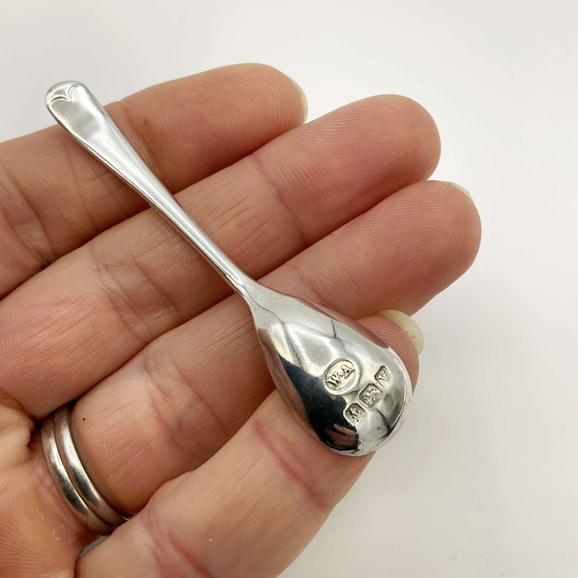 Silver spoon held in a hand against a white background