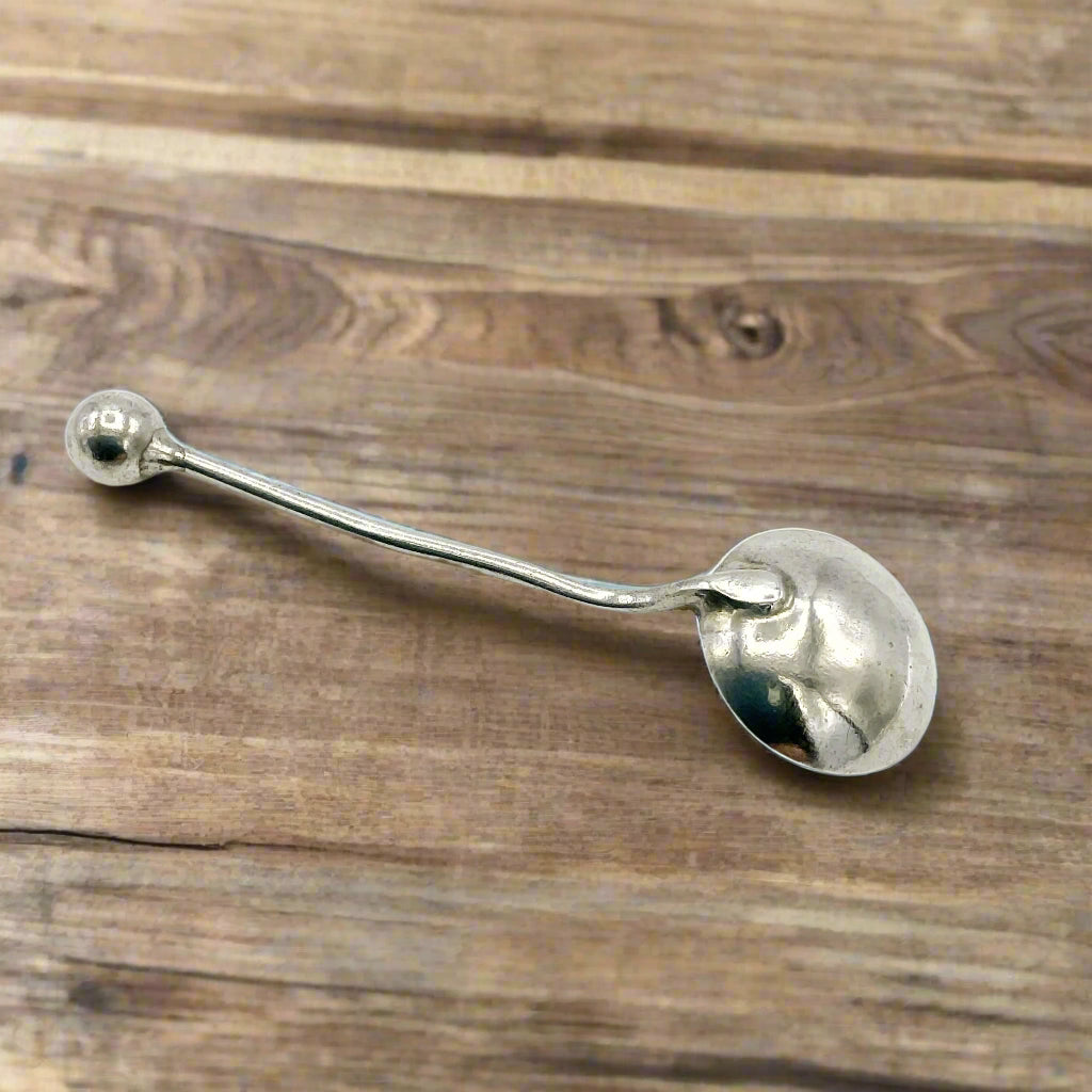 Silver salt spoon upside down on a wooden table