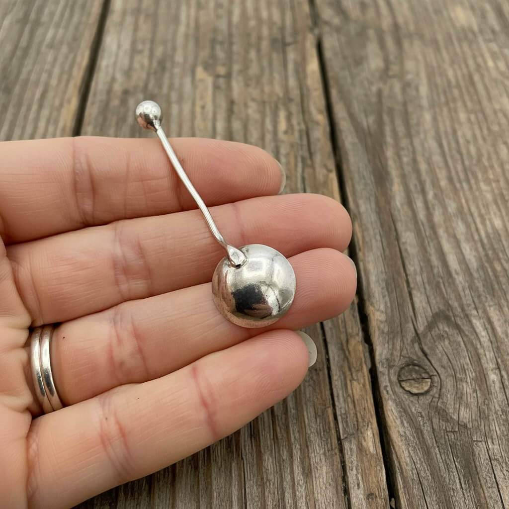 Antique 1902 small sterling silver salt spoon with detailed handle, crafted by Beeches Vintage, placed on a white background.