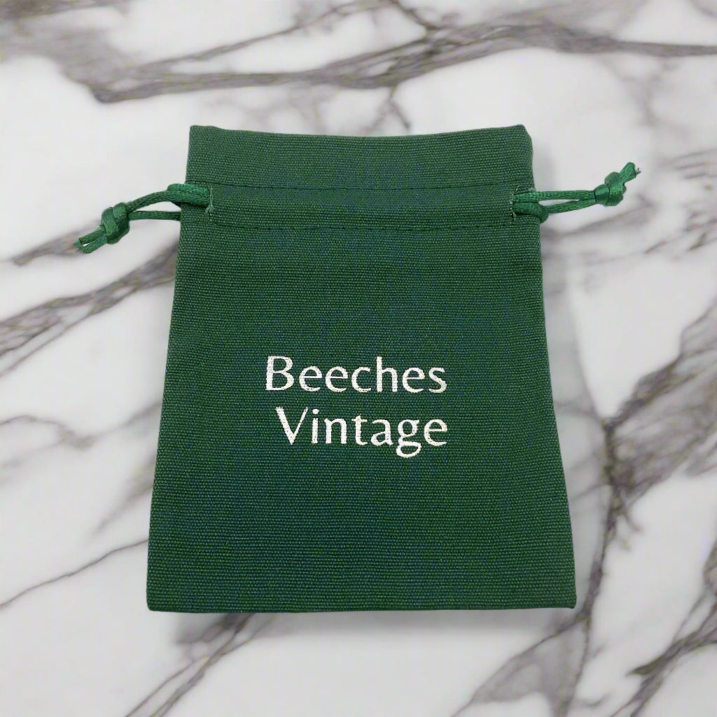 Green drawstring pouch with 'Beeches Vintage' text on a marble worktop