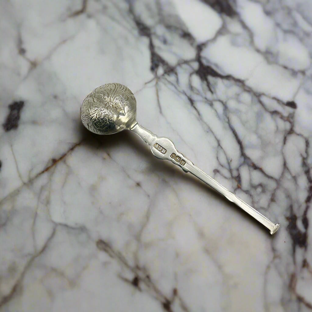 Silver spoon with decorative bowl on a marble worktop