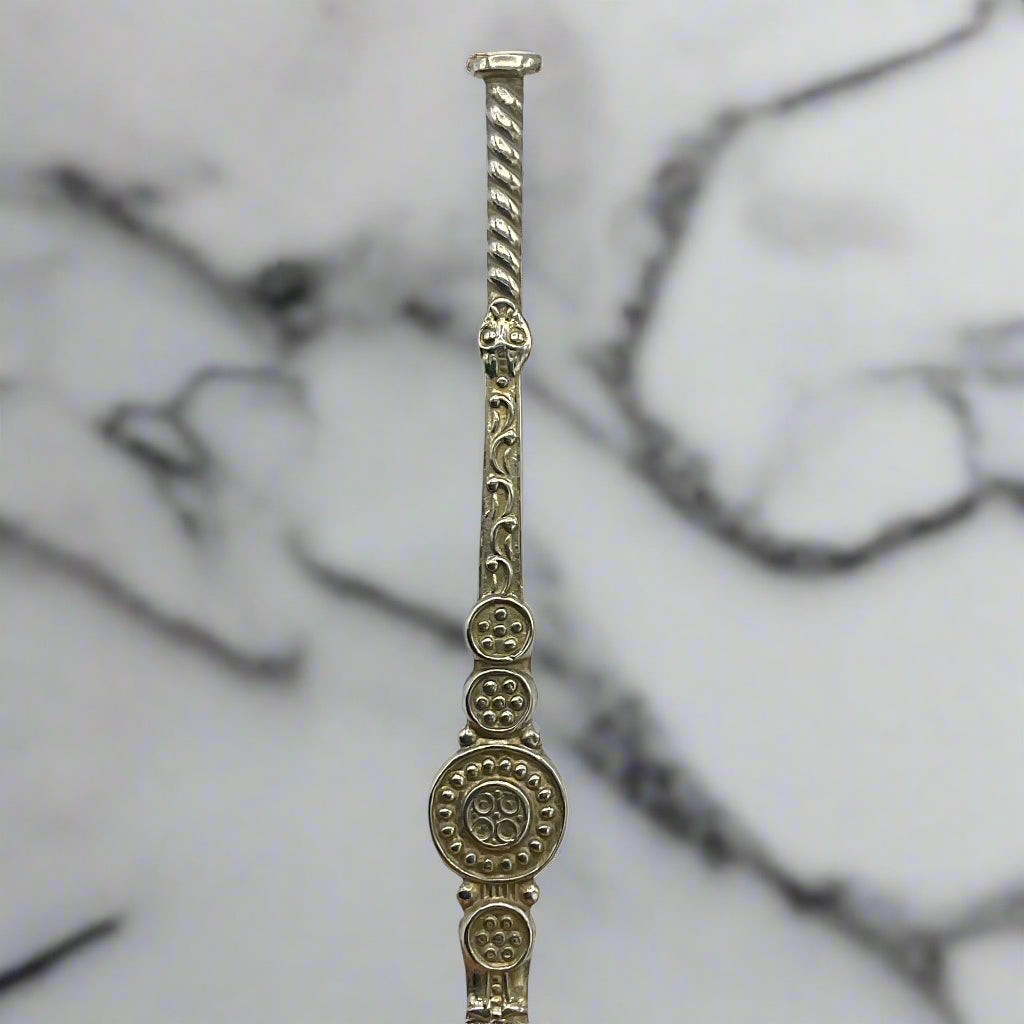 Decorative silver rod with intricate designs on a marble background 