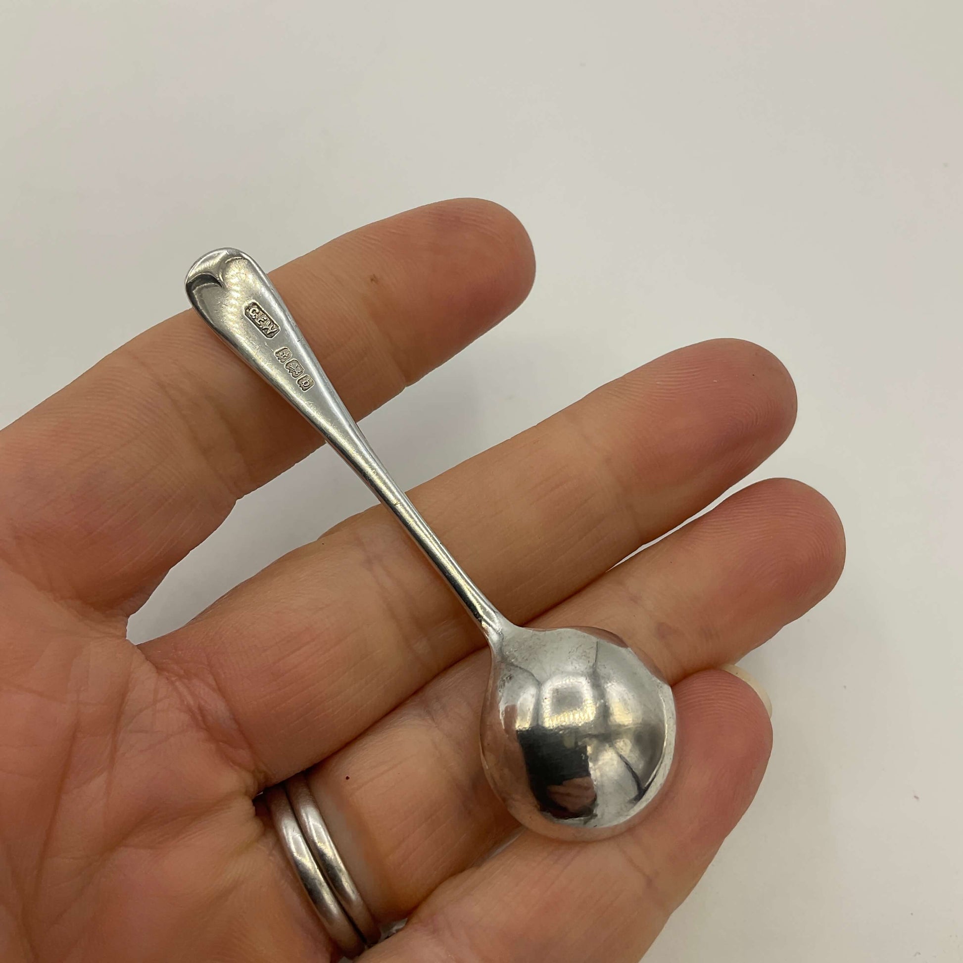 Silver spoon held in a hand against a white background