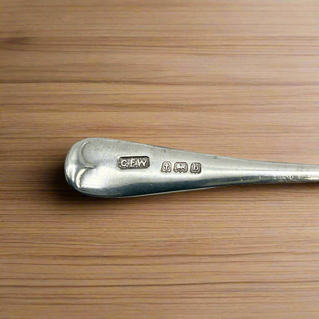 Silver spoon with visible hallmark on a wood table