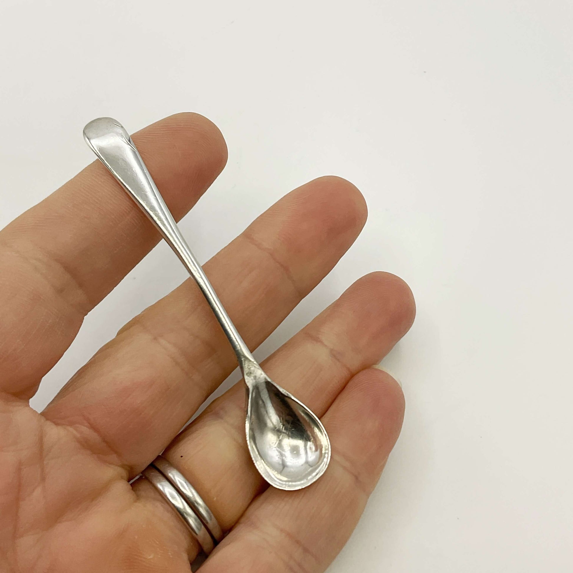 Small silver spoon held between fingers against a white background