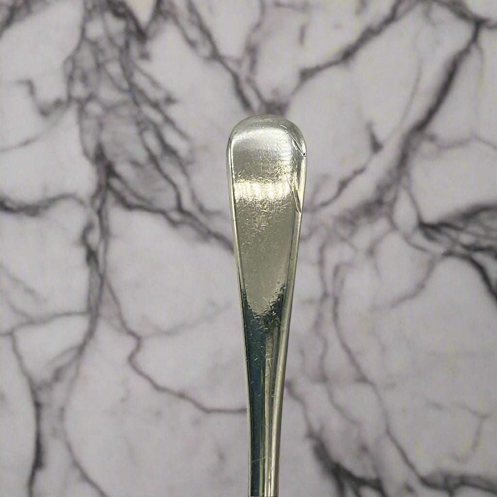 Close-up of a silver spoon handle on a marble worktop background 