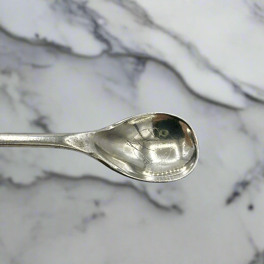 Silver spoon bowl with a marble worktop in the background 