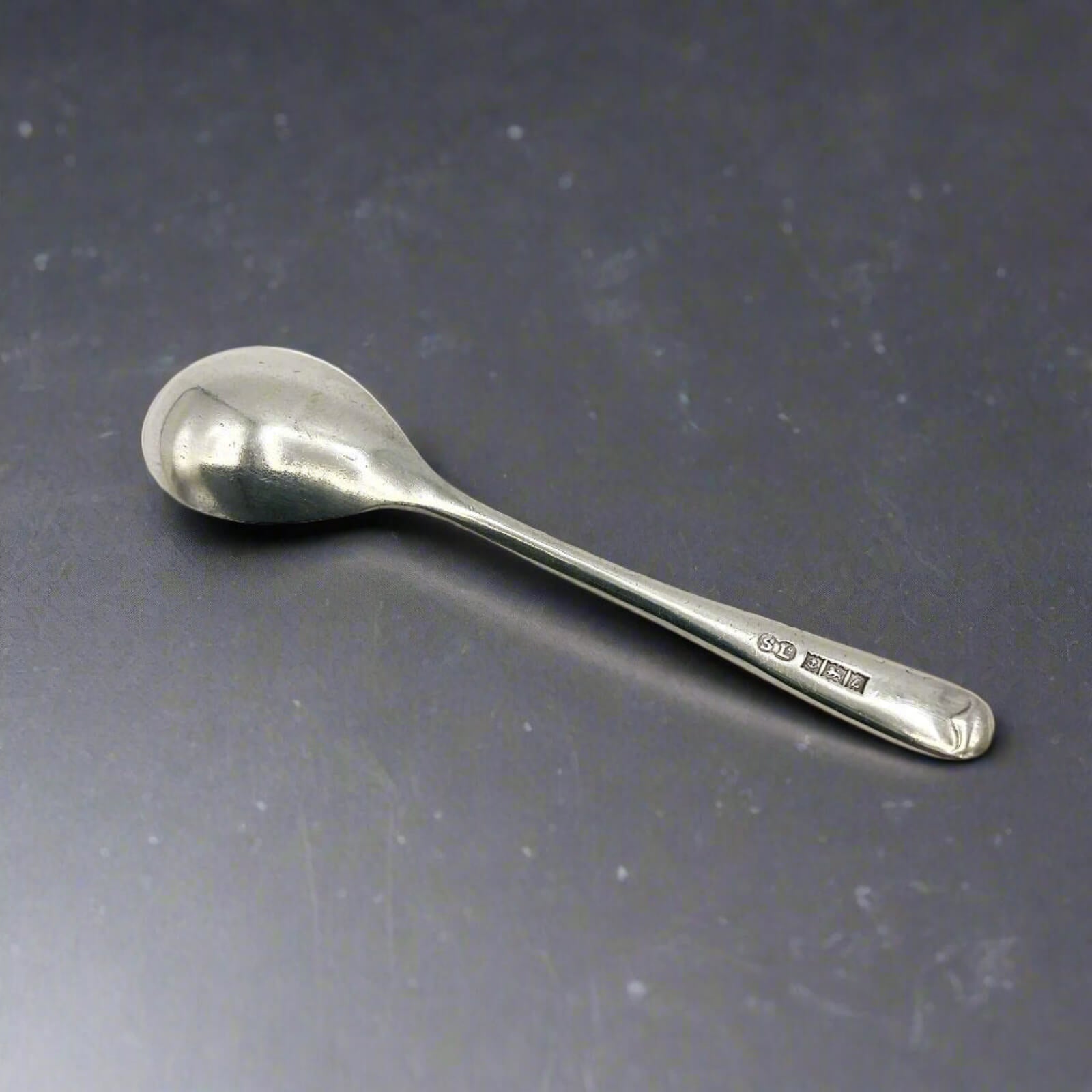 Silver spoon on a reflective gray surface