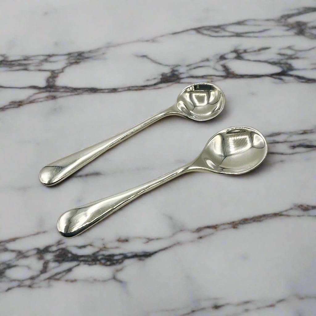 Two silver spoons on a marble worktop