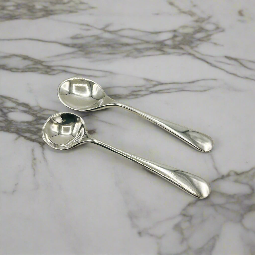 Two silver spoons on a marble worktop