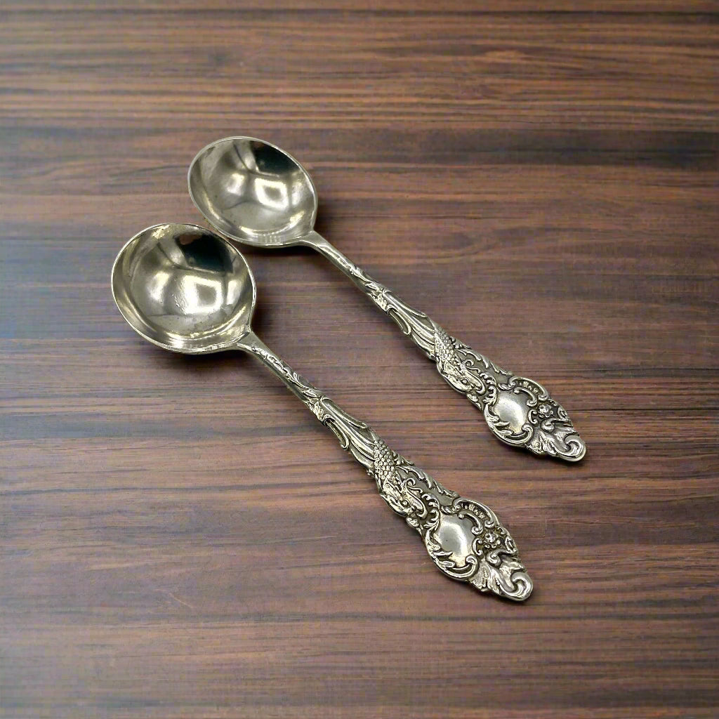 Two ornate silver spoons on a wood table
