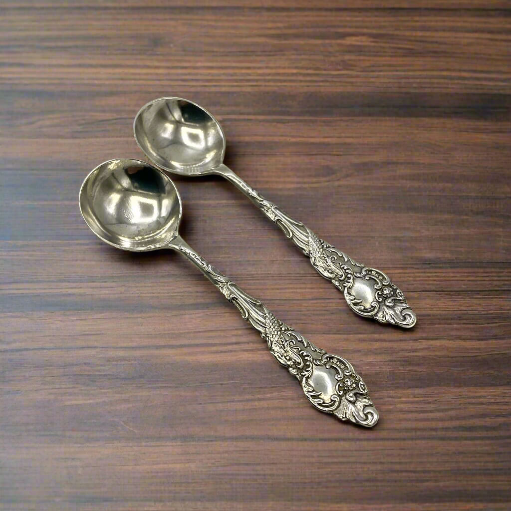Two ornate silver spoons on a wooden surface