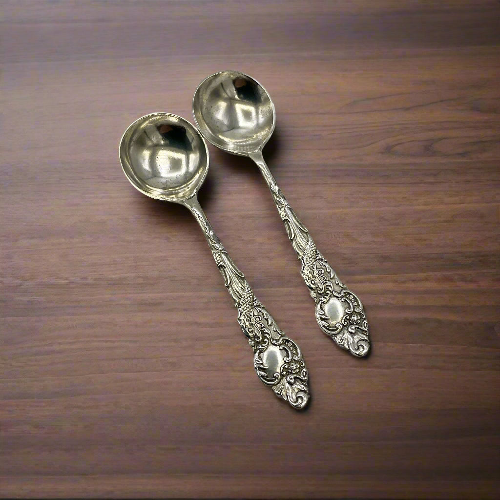 Two ornate silver spoons on a wooden table
