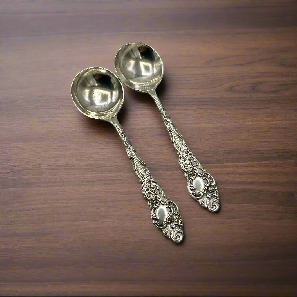 Two ornate silver spoons on a wooden surface