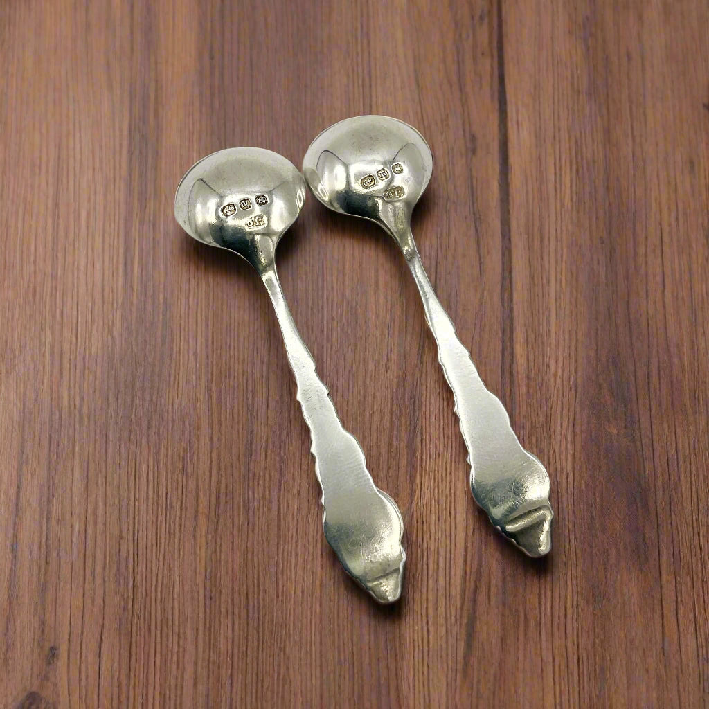 Two silver spoons on a wood table