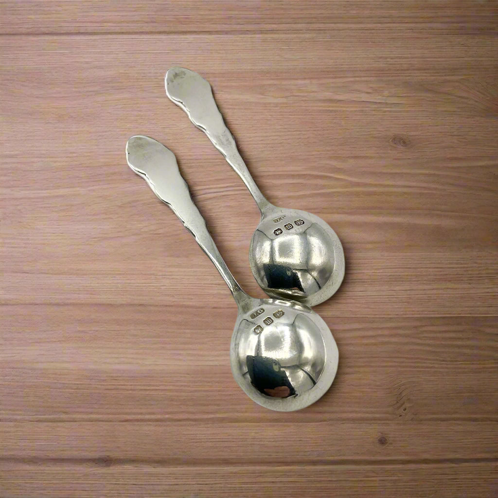 Two silver spoons upside down on a wood table