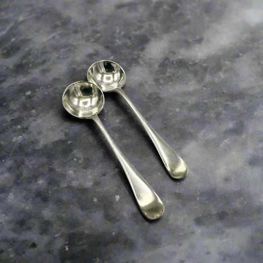 Two silver spoons on a gray stone surface