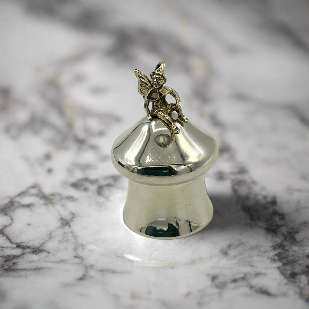 Silver pill box with a fairy figurine on a marble surface