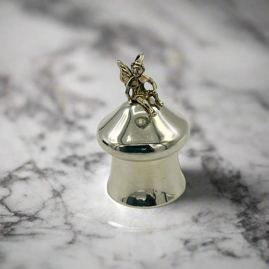 Silver pill box with a fairy figurine on a marble surface