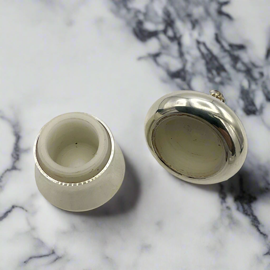 An open silver pill box  on a marble surface