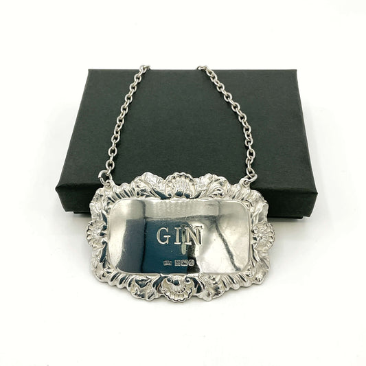 Silver GIN label resting on a black box  on a white background