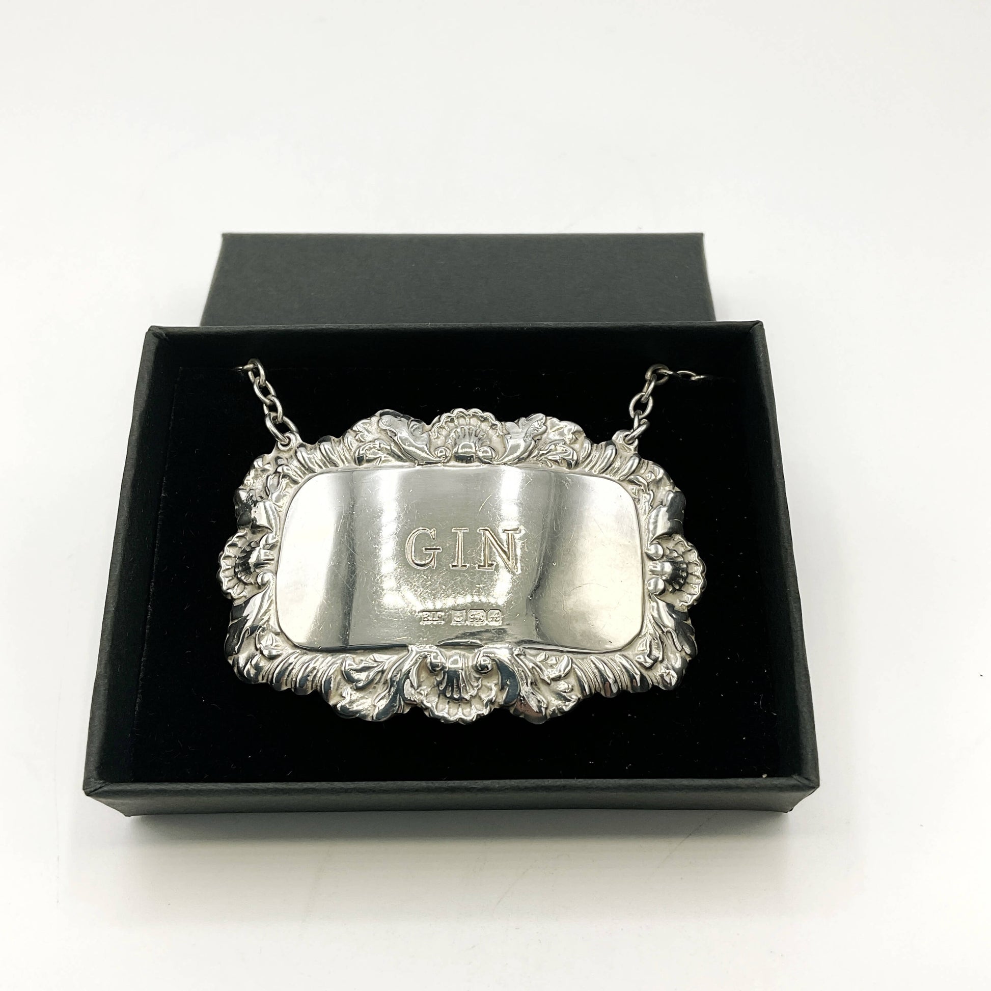 Silver decanter label with 'G.I.N.' engraving in a black box on a white background